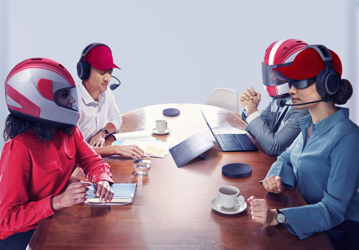 Professionals having a meeting while wearing racing helmets and headsets.